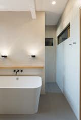 Bath Room, Recessed Lighting, Undermount Sink, Engineered Quartz Counter, Porcelain Tile Wall, Freestanding Tub, One Piece Toilet, Open Shower, Wall Lighting, Porcelain Tile Floor, and Pendant Lighting Clerestory windows in the ensuite ensure natural light enters interior hallways and the master bedroom.  Photo 3 of 11 in Cooper Street Residence by Sarah Brown