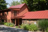 The home is a warm splash of color at the end of a private drive running parallel to a creek and hosta gardens. The taller of the two gables is the original home, with office/bedroom addition on the east side, and dining/kitchen stone additions under the lower gable on the north end.