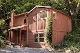 Close to the main house, the guest house is a whimsical structure nestled against the hillside with rear porch looking up into a wooded ravine.