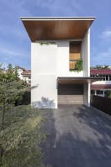 Front facade showing angled white grooved plaster walls and a double volume teak fin screen. 