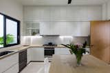 Kitchen, Subway Tile Backsplashe, Refrigerator, Ceramic Tile Floor, Cooktops, Microwave, Undermount Sink, Dishwasher, White Cabinet, Ceiling Lighting, and Wall Lighting Cool white and warm wood palette in wet kitchen.   Photo 10 of 18 in 16A Residence by Studio Roundtop