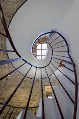 A concrete spiral staircase inside the tower leads to a small landing and a roof terrace.
