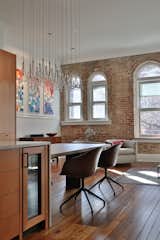 To keep the site lines from the rooms entry to the exposed brick wall, the designer chose a chandelier that both accentuates the height of the space but also, due to its transparency, allows for views through it. 
