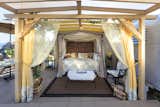 Outdoor bed inside 2 layers of curtains and under a shade structure. Very romantic<><>
