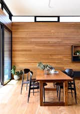 The walls, floors, and ceilings of DS House are clad in timber and concrete, mirroring the style of the exterior facade. The dining room is connected to the living area by a long wooden wall.
