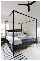 The guest bedroom uses a canopy bed and blue and white bedding to accentuate the sunny attached balcony, where one can look out into the neighborhood, or go to relax and read.