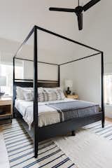 The guest bedroom houses a canopy bed with white, wheat, and black bedding.