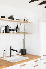 The kitchen area makes use of open shelving and black and white finishes for a crisp look.