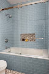 Bathtub features sliding glass doors versus a shower curtain for a clean look. 
Finished in Daltile subway tile in Waterfall.
