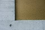 Detail of board-formed concrete facade and bronze intercom panel with etched Japanese floral pattern