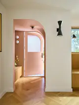 The half arched entry was the only addition to the original home and creates an intentional transition between interior and exterior. The same rose color was used throughout, in the entry, primary bathroom, interior of the skylights, and exterior awnings.
