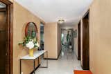 Hallway with grasscloth wallpaper, original flush-mount lights and porcelain tile "faux-terrazzo" tile