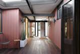 Natural light and greenery combine with wood, glass, and custom-milled exterior siding to give the hallway an open, welcoming feel.