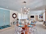 Sky blue doors open onto the intimate dining table, accentuated by transparent seating and dramatic lighting.