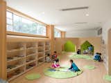 Kids Room, Toddler Age, Shelves, Bookcase, Boy Gender, Light Hardwood Floor, Playroom Room Type, Living Room Room Type, Pre-Teen Age, Girl Gender, and Neutral Gender Area rugs add warmth to the reading stations.  Photos from This Chinese Kindergarten Takes Play Seriously With an Outdoor Climbing Wall