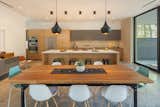 Dining takes place at the large custom-fabricated table underneath pendant lighting. Seating is a mix of Eames Shell Chairs and Real Good chairs from Blu Dot.
