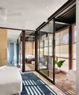 Glass walls bring a sense of brightness to a bedroom and adjacent bathroom.