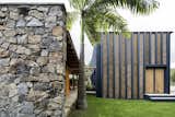 For this holiday getaway on Brazil's Pipa Beach, architecture firm Vilela Florez created two separate volumes, with a series of bridges that connect the bedrooms and open up with glazed sliding doors to the open-plan living area. Along with freestanding walls of natural stone, concrete masonry blocks shape the home's architectural identity, its vertical ribs fitted with bamboo panels arranged in a chevron pattern that help shade the facade.&nbsp;