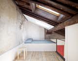 The stripped-down, lofted bedroom is tucked under a slanted roof with generous skylights. Dating from the second half of the 17th century, the wooden ceiling expresses ancient construction techniques that draw from naval culture, recalling the masts of dismantled boats.
