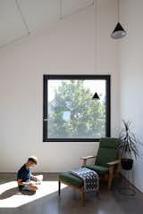 Views of neighboring trees fill the office, where the color green also manifests in a vintage Hans Wegner armchair and ottoman.

