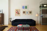 An array of vibrant artworks backdrop Hay’s Mags sofa, paired with a vintage Italian coffee table, Muuto Pull floor lamp, and Moroccan rug from Abra in Budapest.
