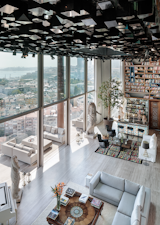 The common area in this penthouse by Studio RHE boasts a digital cube ceiling, stunning views, and an immense book collection by the bar.
