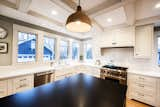 Kitchen, Pendant Lighting, Ceiling Lighting, Medium Hardwood Floor, Dishwasher, Range, White Cabinet, and Range Hood  Photo 20 of 29 in Glen Ellyn Transformation by Liv Companies