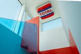 At the top of the staircase, the sign of a TOTAL gas station plays with the colors of the steps and the glass railing.