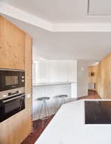 Kitchen, Ceramic Tile Backsplashe, Undermount Sink, Wall Lighting, Wood Cabinet, Marble Counter, Microwave, Terrazzo Floor, Cooktops, and Wall Oven kitchen  Photo 18 of 27 in Tangram house by twobo arquitectura