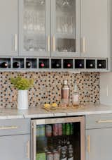 The bar adjacent the dining space highlights some whimsy with this unique backsplash made from wood penny tiles stained in different colors to match the rest of the wood tones in the home. 