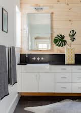 Master bath floating cabinets, reclaimed pine wood walls, and farm sinks carry the consistent design aesthetic throughout the home. 