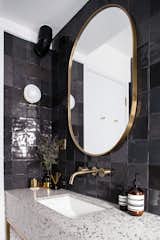 Guest bathroom detail with terrazzo, dark grey tiles, and brass accents