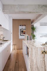 Open kitchen with a mixture of materials such as marble, wood, brass, and untouched concrete beams from the apartment's abandoned past, mixing the old and the new