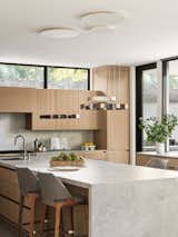 Kitchen with adjustable modern pendants and porcelain counters and backsplash