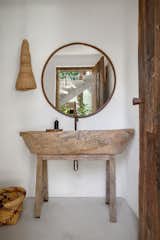 The toilet has a rustic wooden countertop and a copper-framed mirror

