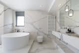 Bath Room, Marble Counter, One Piece Toilet, Ceiling Lighting, Marble Wall, Freestanding Tub, Wall Mount Sink, and Pendant Lighting The marble element dominates the bathroom of the master bedroom.  Photo 6 of 19 in Eos Urban Villa by 3NK Engineers & Architects