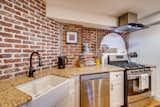 Kitchen, Granite Counter, Range, Bamboo Floor, Drop In Sink, Brick Backsplashe, and Range Hood  Photo 12 of 21 in Bright Garden Level Dwelling by Virtuance Real Estate Photography