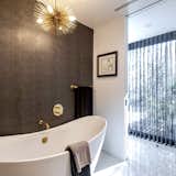 The freestanding tub with leather pattern wall is filled with light from the courtyard.