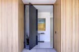 The entry features a custom black steel pivot door.