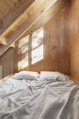 The bed is suspended in a lofted area above the living room.