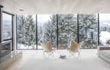 Framed snowy views from upper floor to ski hills beyond through wall to wall full height windows