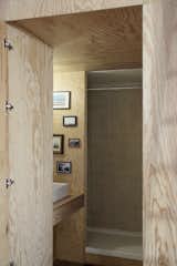 The bathroom is fitted with pine plywood and minimally decorated with framed photographs.
