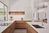 Kitchen, Undermount Sink, Engineered Quartz Counter, Wood Cabinet, Dishwasher, Pendant Lighting, Range, Beverage Center, Stone Slab Backsplashe, Porcelain Tile Floor, and White Cabinet  Photo 12 of 23 in House Perched in the Trees by Tracy A. Stone Architect