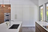 Kitchen, Pendant Lighting, Refrigerator, Wall Oven, Engineered Quartz Counter, Porcelain Tile Floor, Wood Cabinet, Undermount Sink, and White Cabinet  Photo 13 of 23 in House Perched in the Trees by Tracy A. Stone Architect