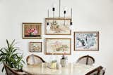 A modern light fixture is paired with vintage furniture and a boho chic gallery wall in this dining room.