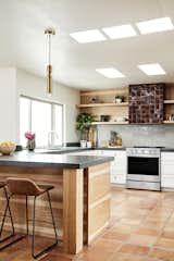 Traditional Saltillo tile are juxtaposed by warm, earthy tones throughout this bright, airy modern kitchen.