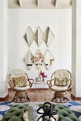 Rattan chairs sit below gold diamond mirrors that draw your eye up to the high ceilings in this living room. Textures and color add in additional interest.