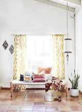 A vintage daybed filled with colorful, textured pillows sits on beautiful Saltillo tile. We hung graphic yellow curtains behind it, to frame the space, and centered the daybed on a big window that looks out to a pool.