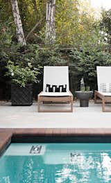 Cream loungers and dark stone side tables line the edge of the pool with black and white subway tile accents.