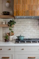 Cream subway tile backsplash is the perfect backdrop for a custom built amber tile wrapped kitchen hood.